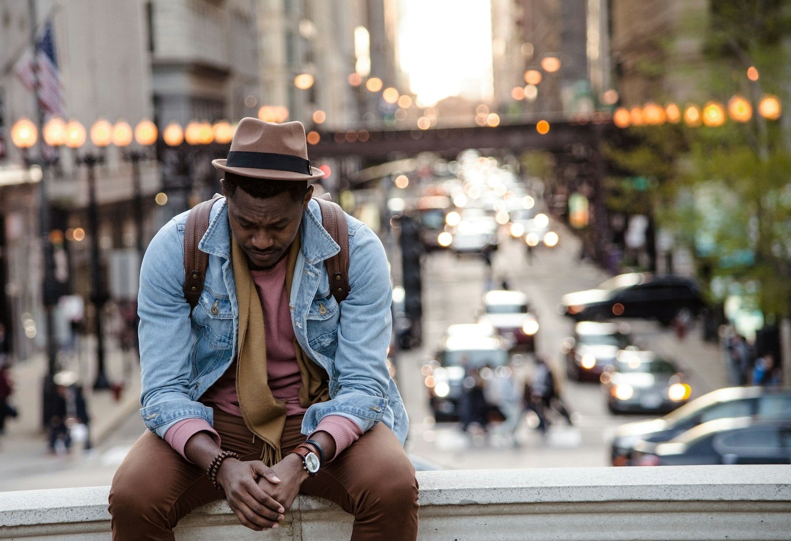 Oración por un trabajo digno, A man in a leather jacket looking down while sitting on a ledge in a city