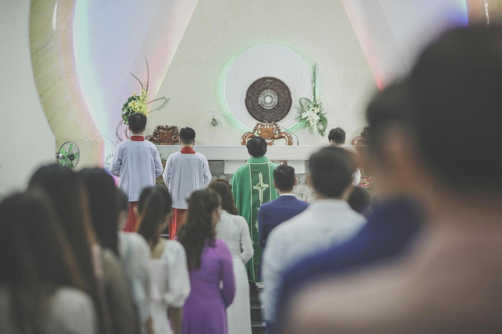 obligación o regalo, A group of people participating in a Catholic mass ceremony in a church, led by a priest in green vestments.